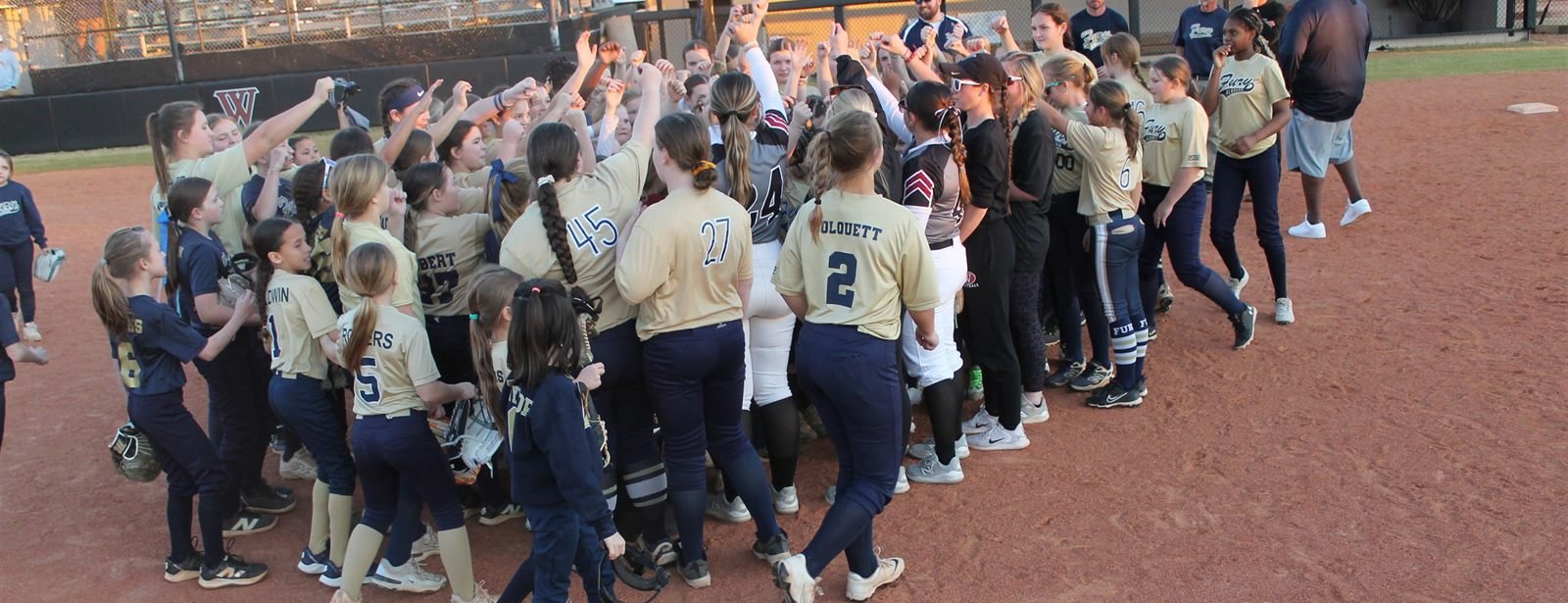 The whole Fury organization packed into a huddle with hands raised at golden hour